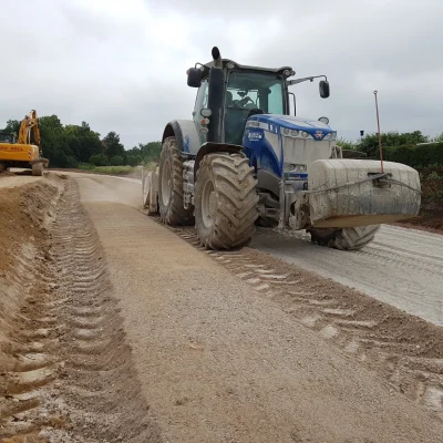 Ein Traktor mit Anbaustabilisierer fährt einem Weg entlang