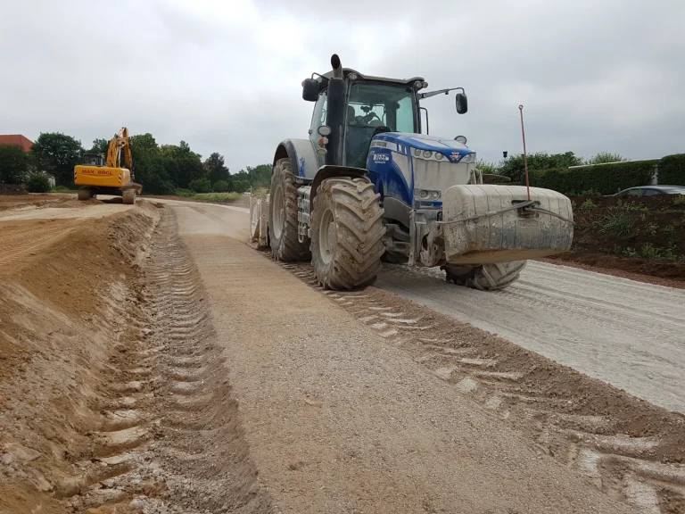Ein Traktor mit Anbaustabilisierer fährt einem Weg entlang